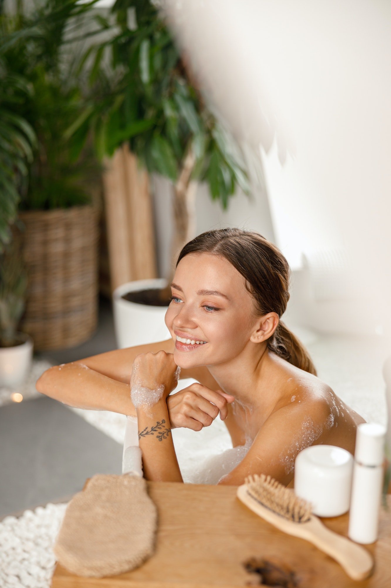 Joyful Young Woman Smiling Away And Leaning On Bathtub Side While Bathing At Spa Resort.jpg